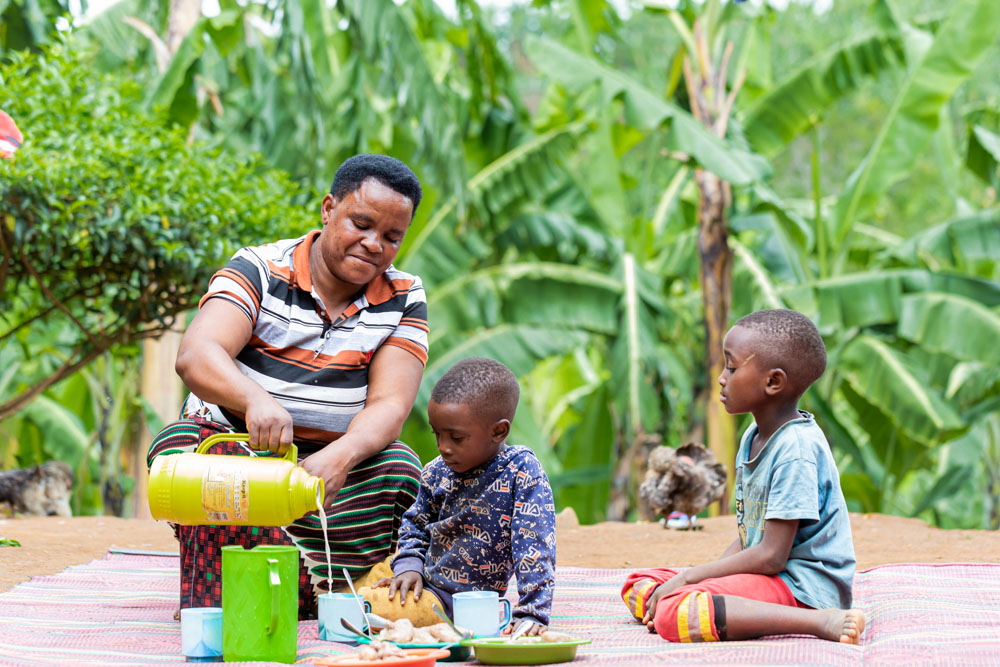 A woman pours glasses of milk for two boys in Tanzania. 