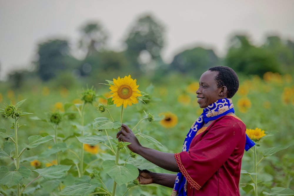 A woman holding a sunflower in a field. 