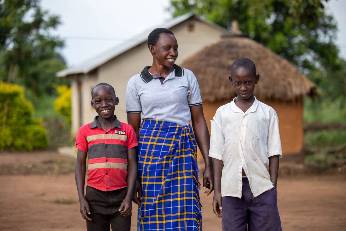 A smiling woman standing with her two young kids.