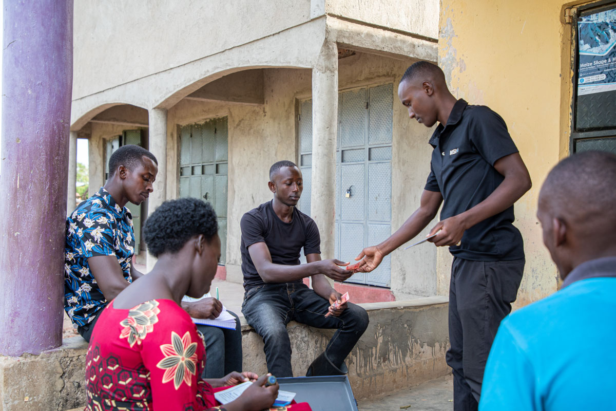 A man collecting money from another man in a group of young people.