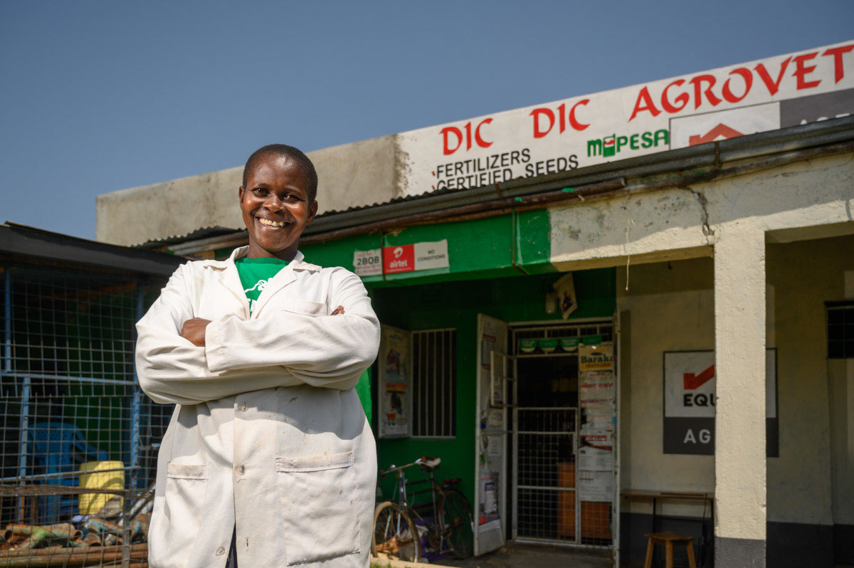 A woman poses in front of an agrovet shop in Kenya.