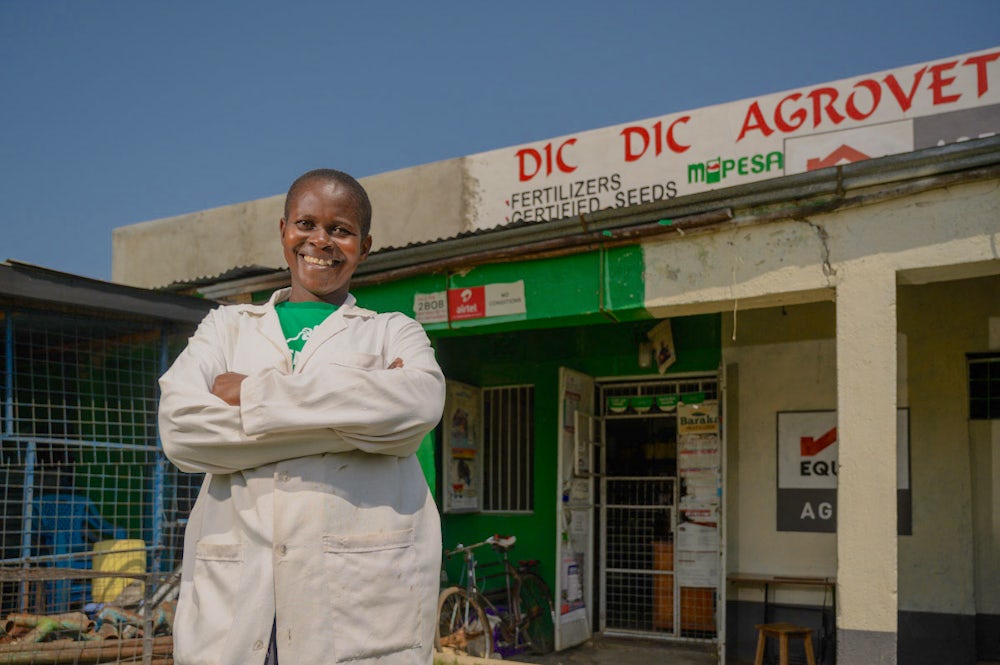 A woman poses in front of an agrovet shop in Kenya.