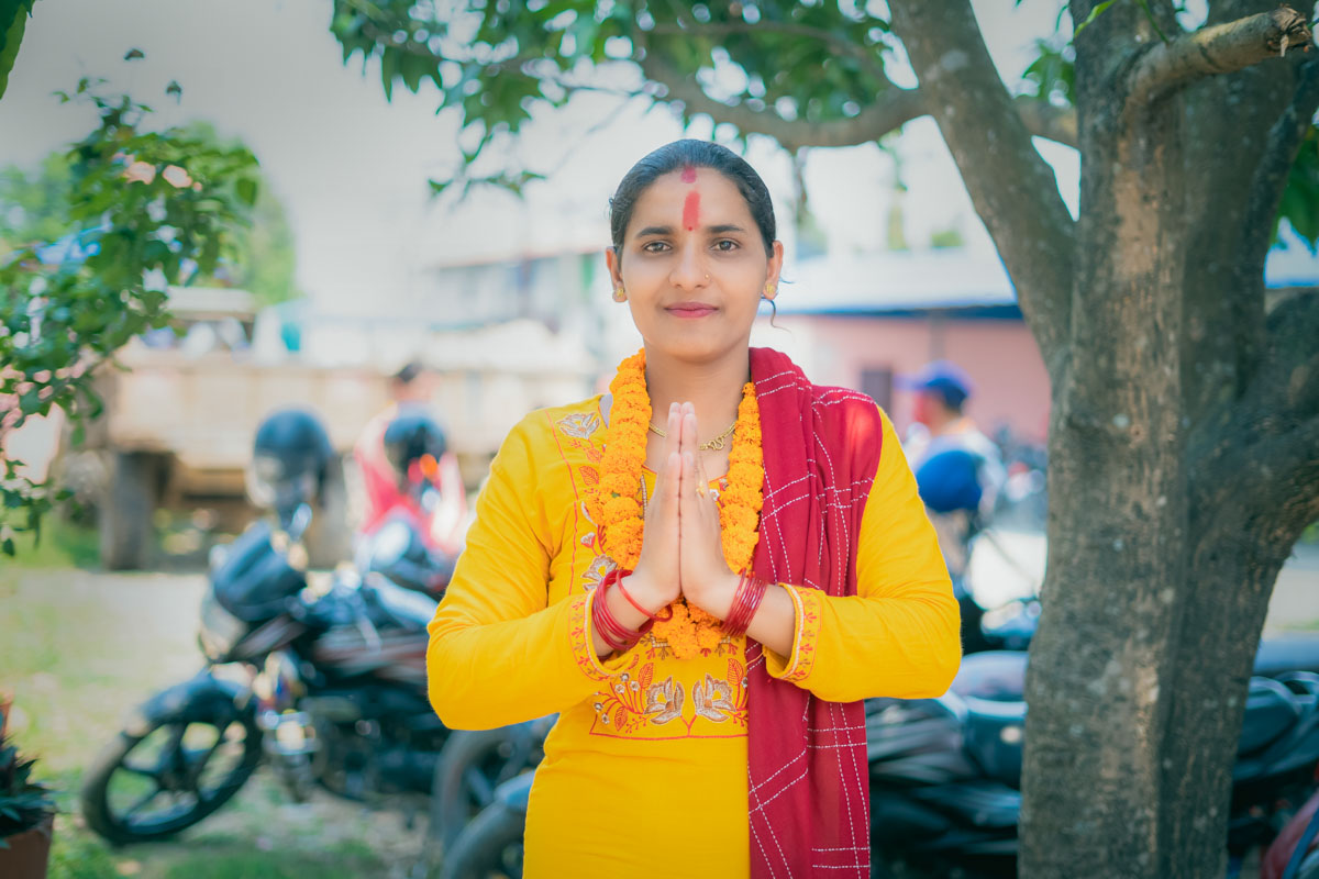 A Nepali woman poses for a portrait with her hands in prayer position.