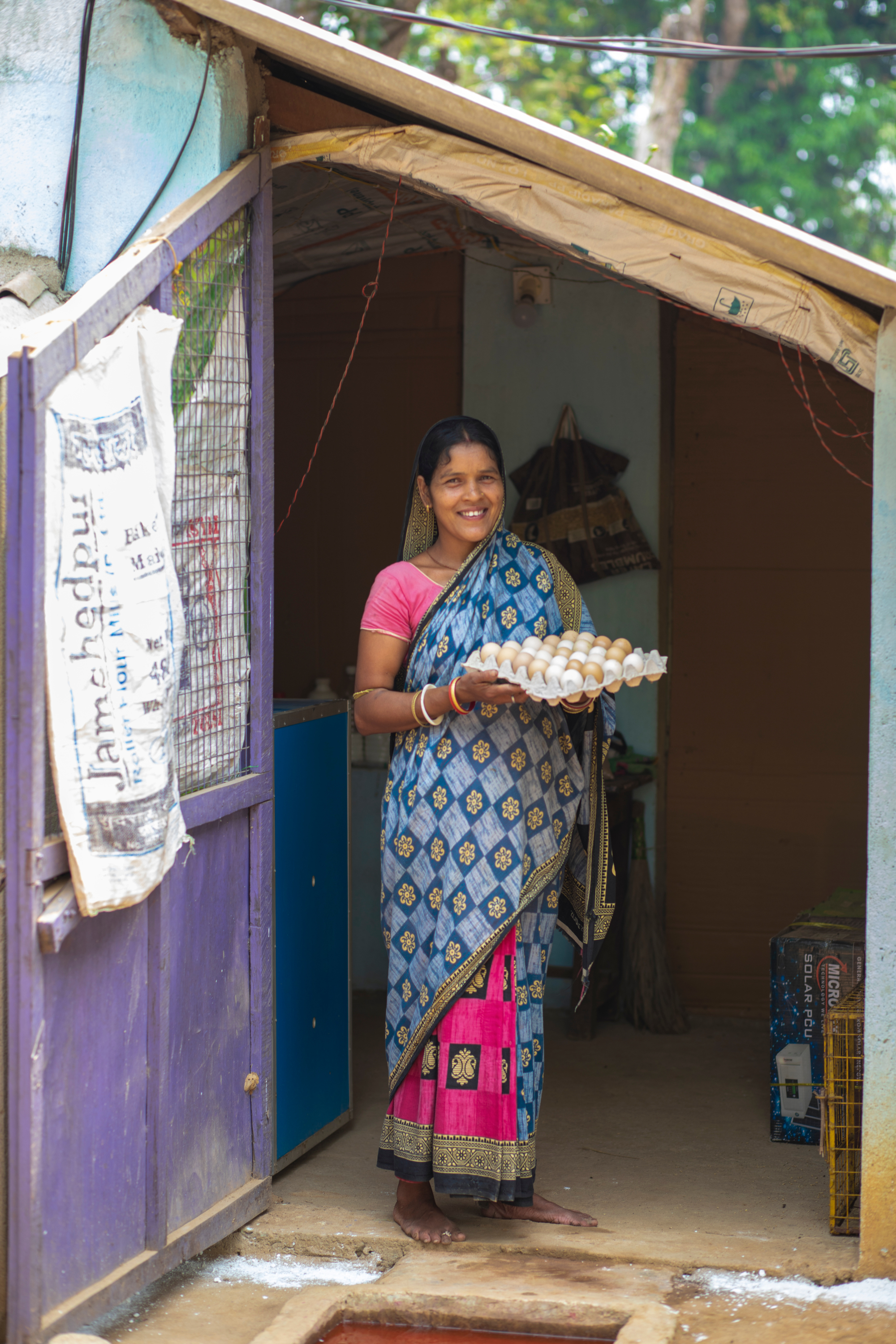 A woman standing holding an egg tray.