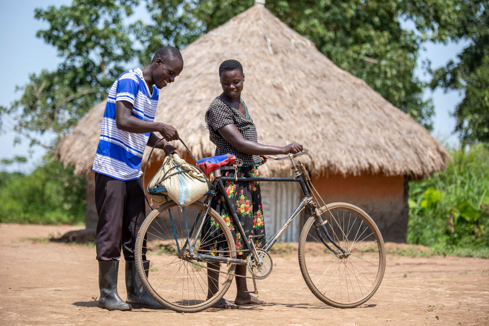 Evaluation helps Innocent load groundnuts onto their bicycle carrier. 