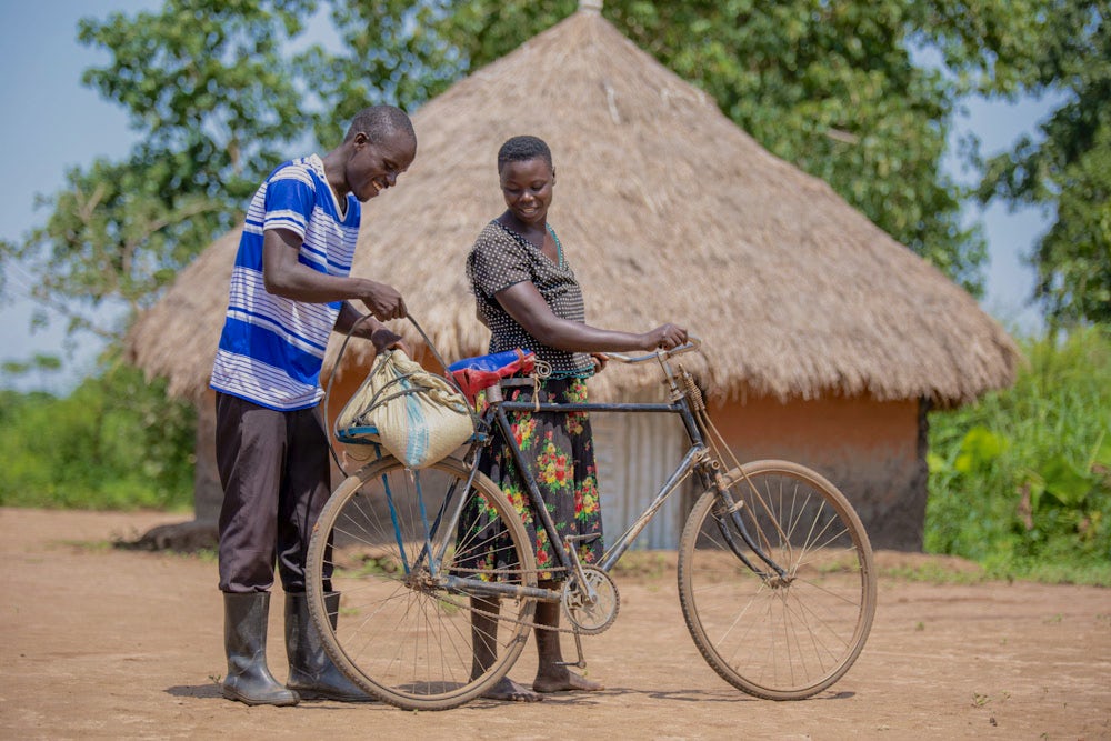 Evaluation helps Innocent load groundnuts onto their bicycle carrier. 