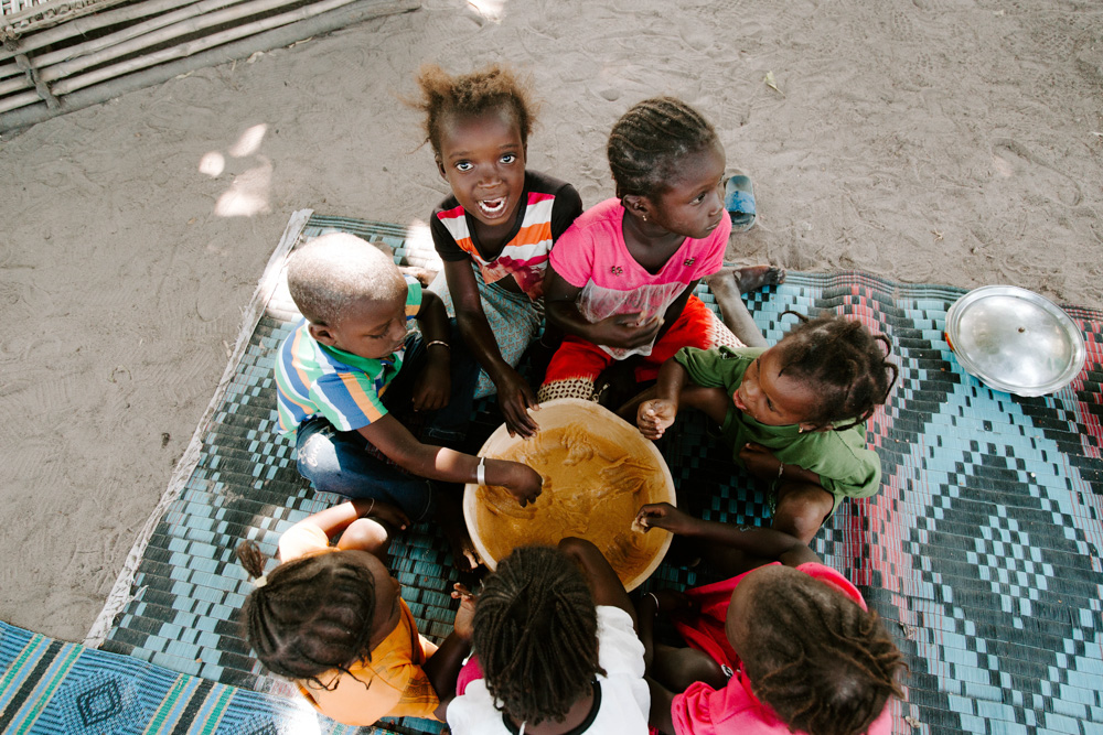 Children sitting in a circle eating nutrient-dense food from a bowl.