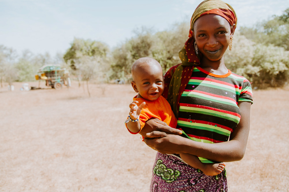 A woman holding her baby and smiling.