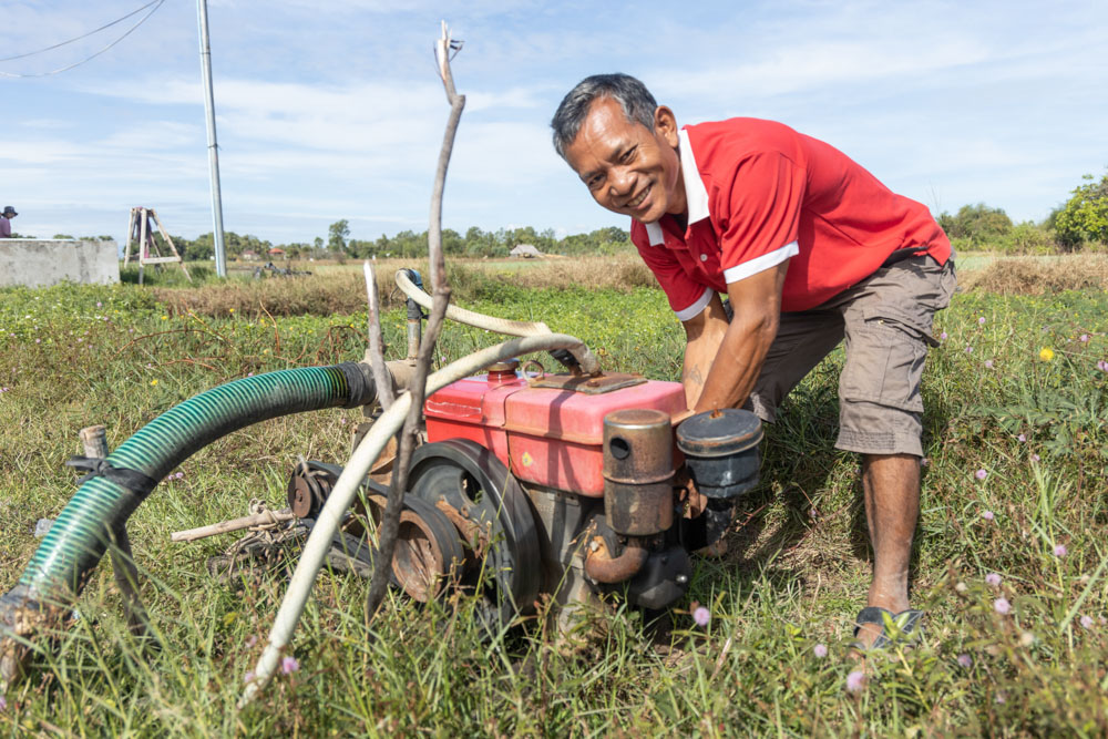 Sun Sythol starts a gas water pump to irrigate his green onion fields.