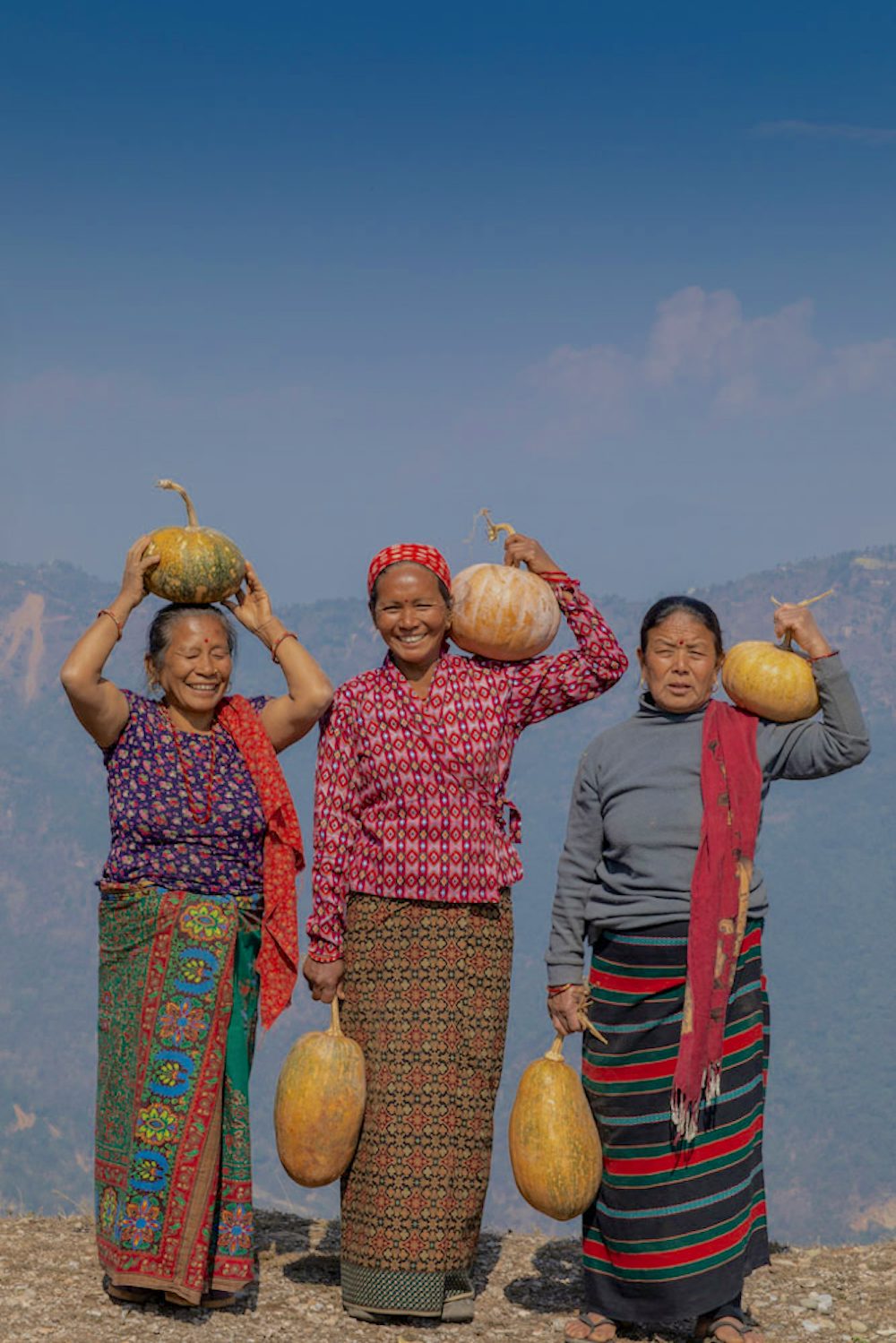 Three women stand with pumpkins ready for delivery in Boughaghuma village, Palpa, Nepal.