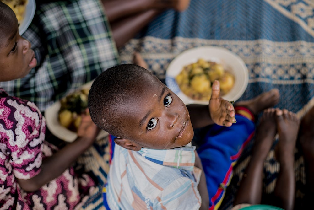 A young child sits with a plate of food.