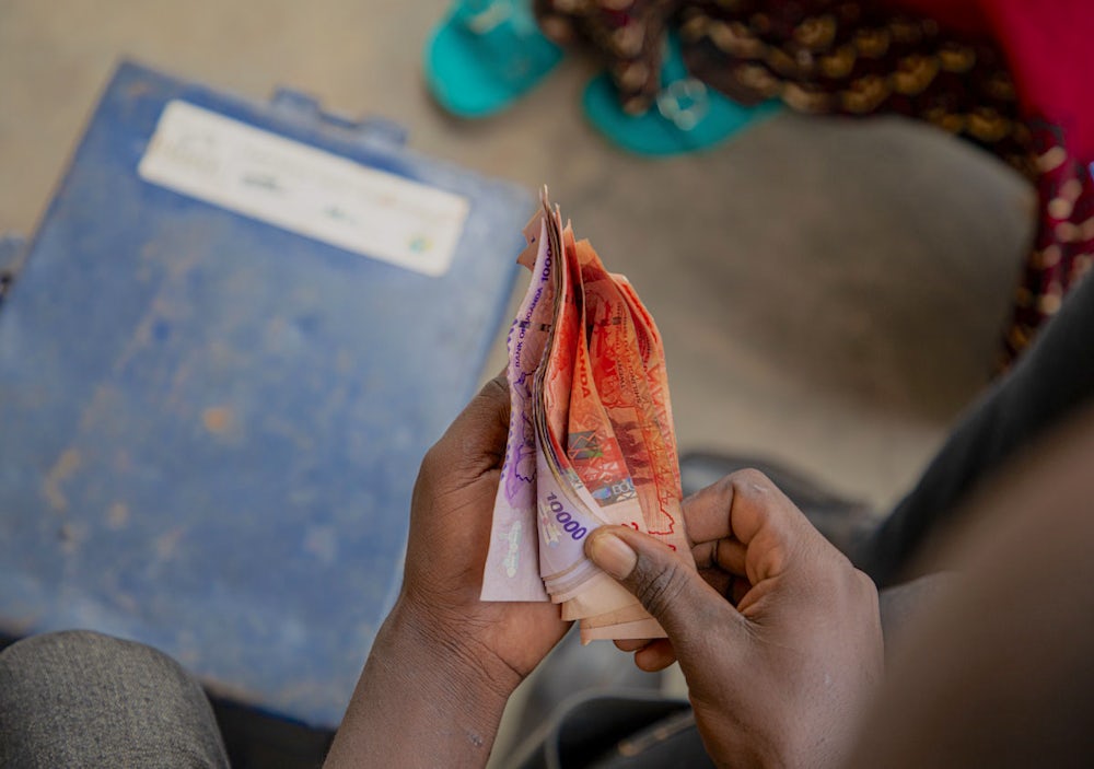 Hands count a stack of bills in Uganda.
