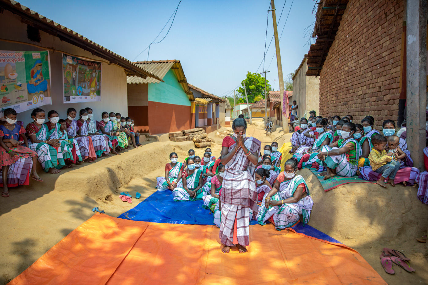A woman bows to the camera in front of a group of women.